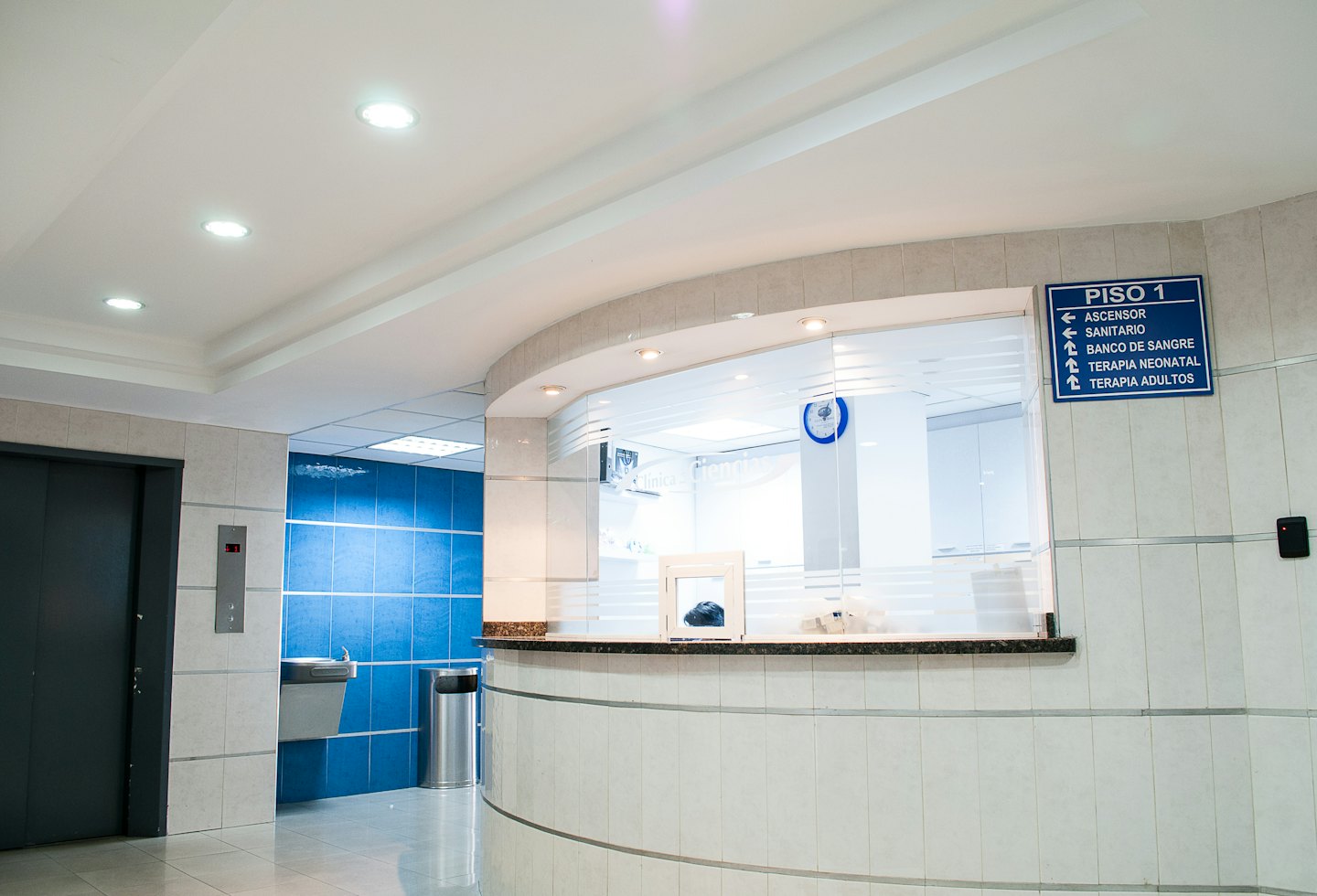 Moderne Empfangshalle mit geschwungener Theke und blauen Fliesen.